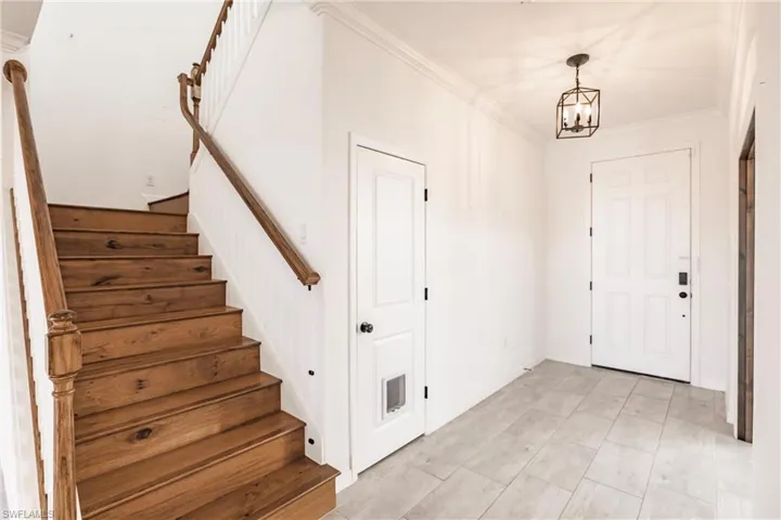 Entryway with crown molding and an inviting chandelier
