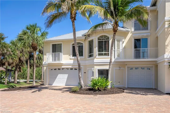 Townhome / multi-family property with a garage, stucco siding, and decorative driveway