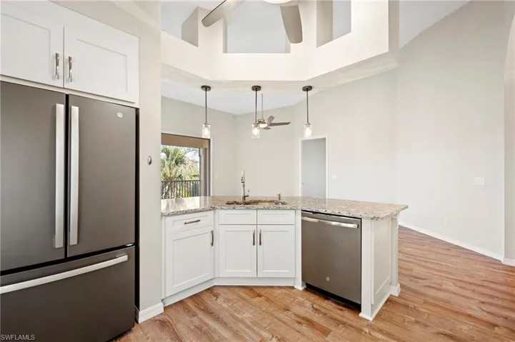 Kitchen with a sink, ceiling fan, appliances with stainless steel finishes, light vinyl style floors, and light stone countertops