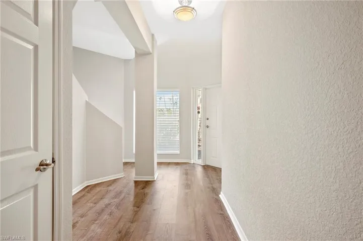 Foyer entrance with a textured wall, baseboards, and wood finished floors