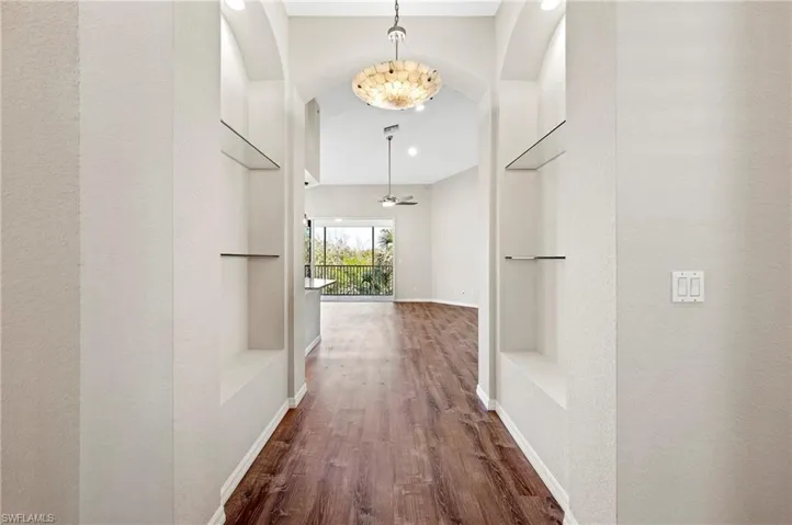 Hallway featuring arched walkways, wood finished floors, baseboards, and recessed lighting