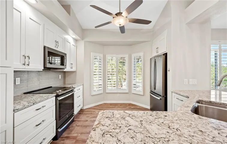 Kitchen with white cabinets, luxury vinyl  finished floors, a sink, stainless steel appliances, and backsplash