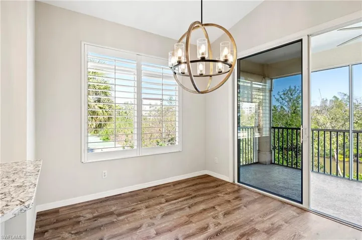 Unfurnished dining area featuring a healthy amount of sunlight, a notable chandelier, baseboards, and luxury vinyl  finished floors