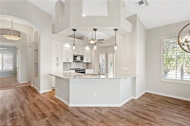 Kitchen with arched walkways, white cabinets, visible vents, appliances with stainless steel finishes, and a sink