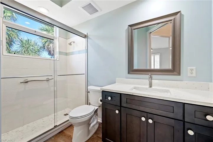 Full bathroom with vanity, a stall shower, toilet, visible vents, and tile floors