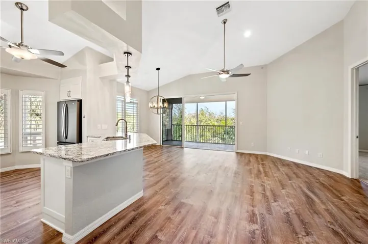 Kitchen featuring a sink, freestanding refrigerator, wood finished floors, and ceiling fan with notable chandelier