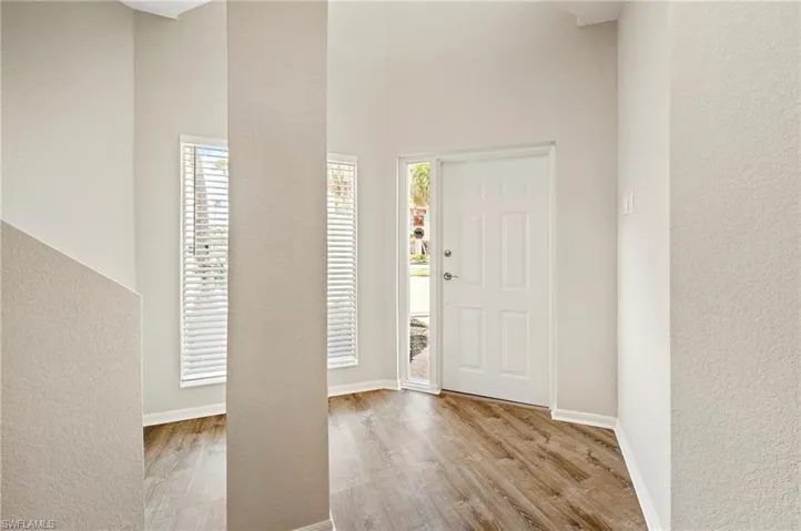 Entryway with a textured wall, baseboards, a towering ceiling, and wood finished floors