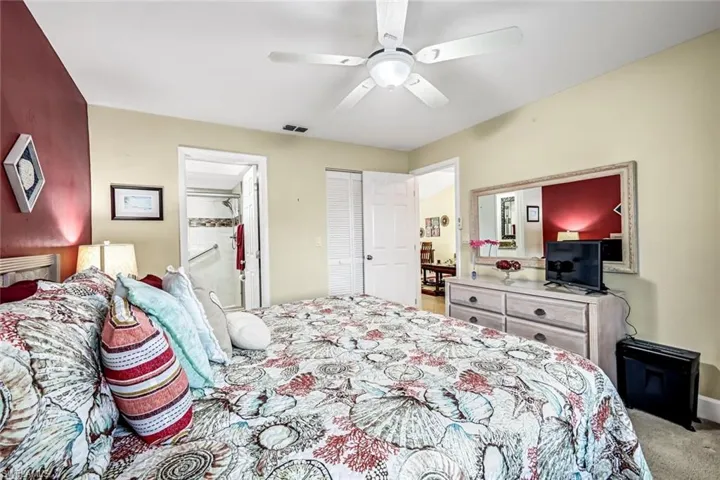 Bedroom with ensuite bath, ceiling fan, and carpet flooring.