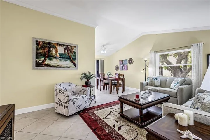 Living area featuring 18" tile flooring, crown molding, and vaulted ceiling.