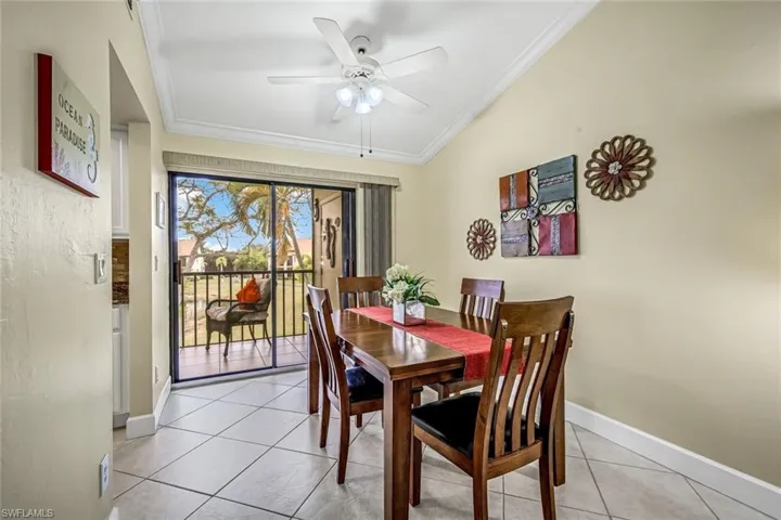 Dining room with crown molding, tile flooring, and vaulted ceiling.