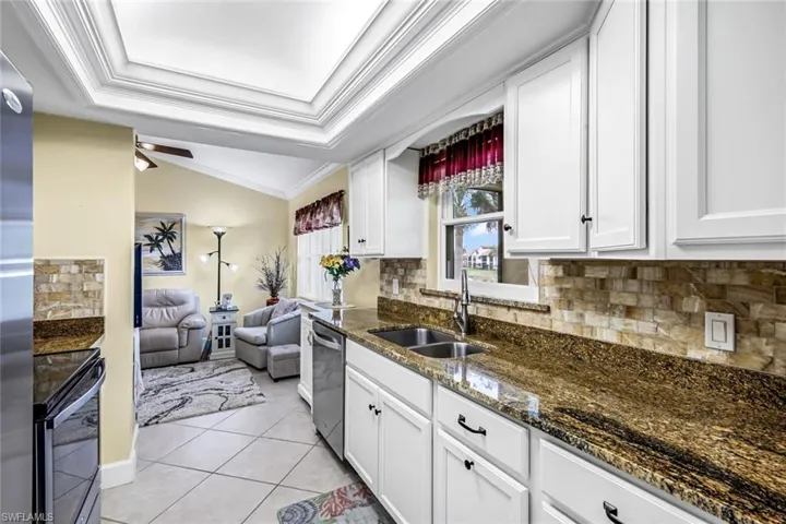 Kitchen featuring stainless steel appliances, backsplash, granite countertops, and tray ceiling.