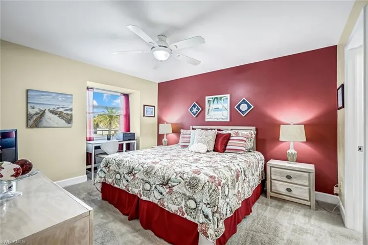Bedroom featuring light carpet, a ceiling fan, and an accent wall.