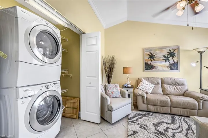 Laundry area featuring stacked washer and dryer with extra storage & bi-fold doors.