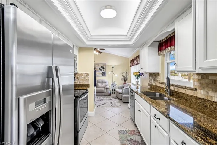 Kitchen featuring stainless steel appliances, backsplash, granite countertops, and tray ceiling.