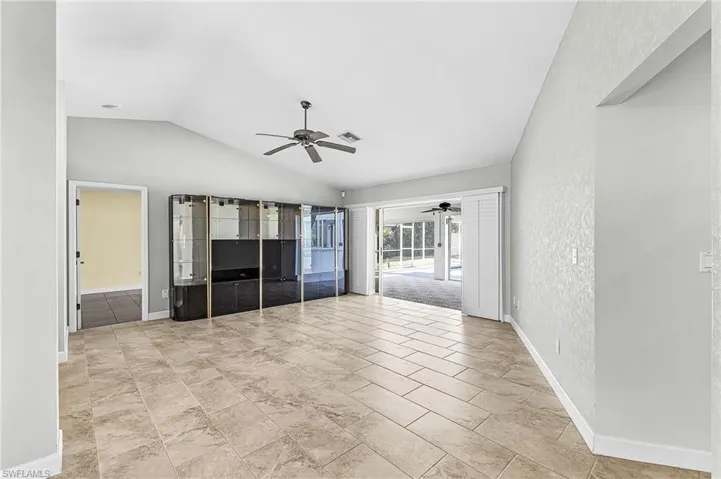 Living room featuring sliders to the pool area, lofted ceiling, and a ceiling fan