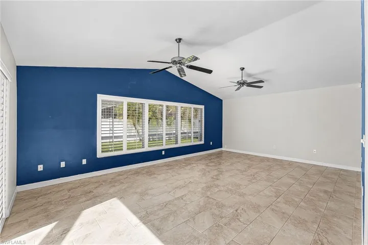 Unfurnished room with a ceiling fan and lofted ceiling