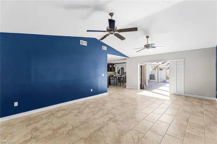 Family  room with a ceiling fan and vaulted ceiling and sliders to the lanai and plantation shutters