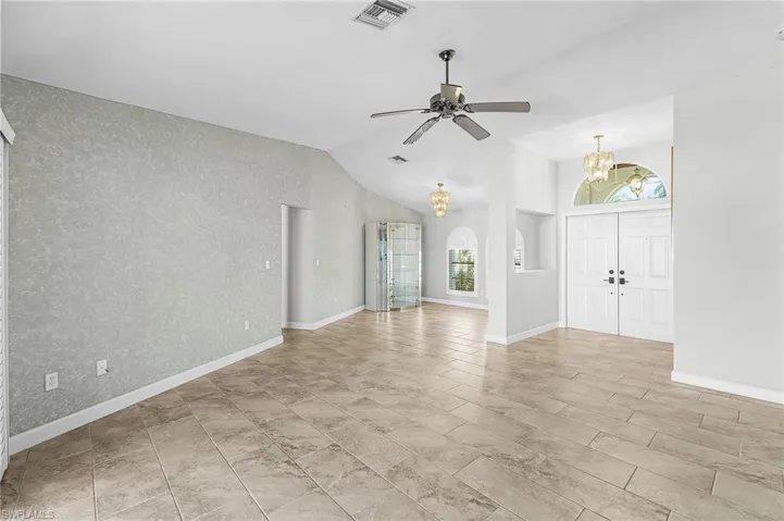 Unfurnished living room with a chandelier,  ceiling fan, and vaulted ceiling