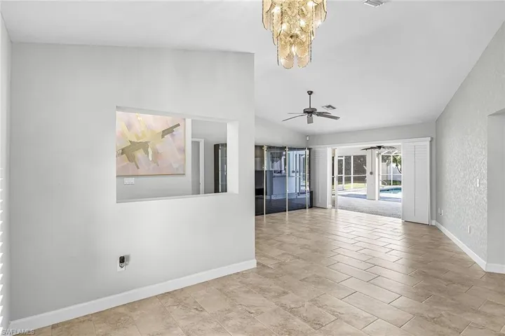 Living room featuring lofted ceiling and ceiling fan with triple sliders to the lanai and pool area