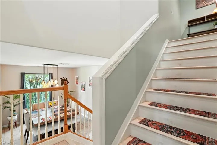 Bright and airy upstairs hallway with recessed lighting, neutral gray walls, and modern wood-look flooring. Multiple doors lead to spacious bedrooms and baths, while decorative wall accents and stylish rugs add warmth and character. The open railing overlooks the lower level, creating a connected, open feel. Perfect for families or guests, this versatile upper-level layout enhances functionality and flow in this beautiful Southwest Florida home