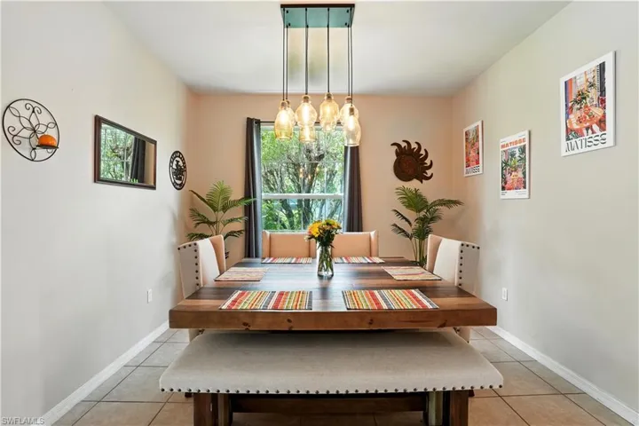 ChatGPT said:Elegant dining room with warm neutral walls, tile flooring, and a stunning modern light fixture that creates a welcoming ambiance. A large window fills the space with natural light and provides serene views of the lush greenery outside. Perfect for entertaining or family meals, this inviting space offers a stylish setting that blends comfort and sophistication
