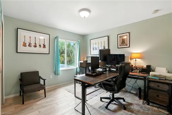 Versatile bedroom or home office with sleek dark gray walls, wood-look flooring, and a large window bringing in natural light. Ample space for desks, shelving, or creative setups makes it perfect for work-from-home, gaming, or hobbies. LED accent lighting adds a modern touch, while the neutral palette allows for easy personalization.