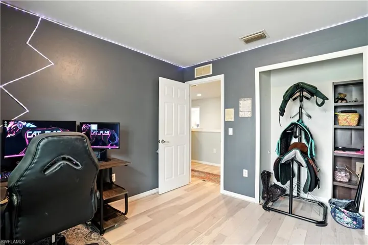 Versatile bedroom or home office with sleek dark gray walls, wood-look flooring, and a large window bringing in natural light. Ample space for desks, shelving, or creative setups makes it perfect for work-from-home, gaming, or hobbies. LED accent lighting adds a modern touch, while the neutral palette allows for easy personalization.
