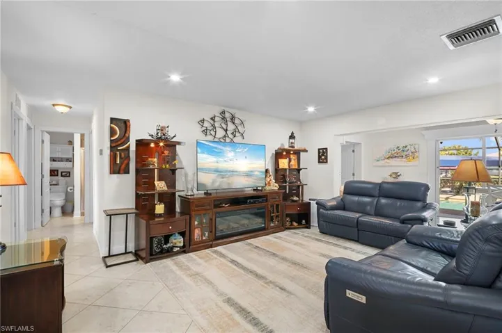 Living room featuring light tile patterned flooring, a glass covered fireplace, and recessed lighting