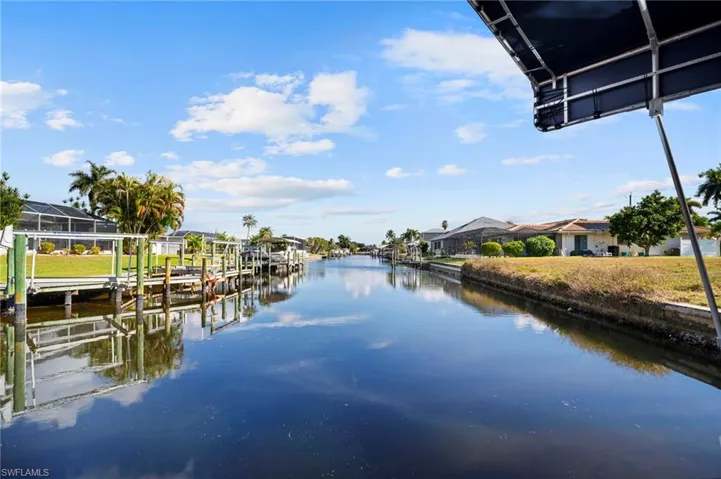 Dock area with a water view, boat lift, and a residential view