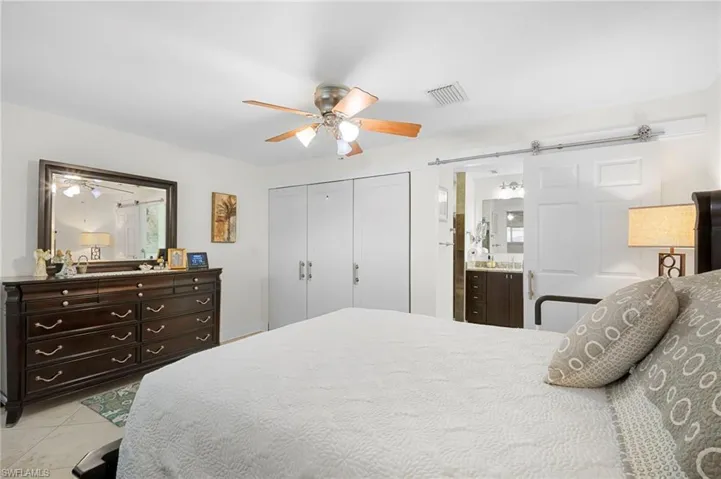 Bedroom with a closet, ceiling fan, ensuite bath, and light tile patterned floors