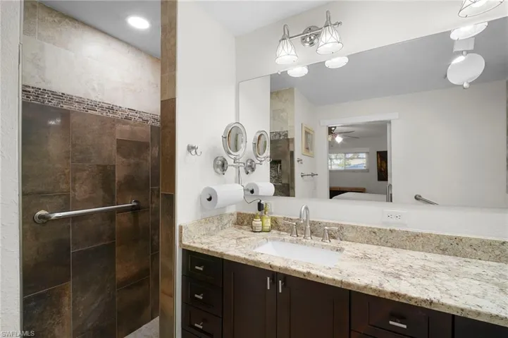 Full bath featuring vanity, connected bathroom, walk in shower, and a ceiling fan