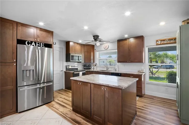 Kitchen featuring stainless steel appliances, a center island, light wood finished floors, ceiling fan, and recessed lighting