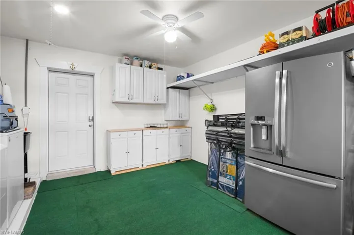 Kitchen with stainless steel refrigerator with ice dispenser, dark carpet, white cabinets, a ceiling fan, and light countertops