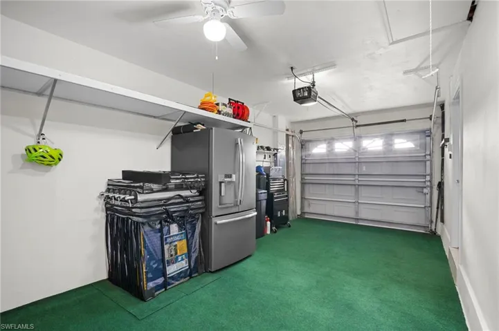Garage with stainless steel fridge, a ceiling fan, and a garage door opener