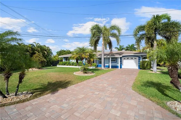 Ranch-style home with a front yard, an attached garage, and decorative driveway