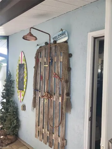Outdoor shower featuring a copper rain shower head, handheld sprayer, and rustic wood panel backing