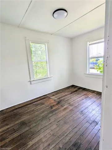 Unfurnished room with a healthy amount of sunlight and dark hardwood / wood-style flooring