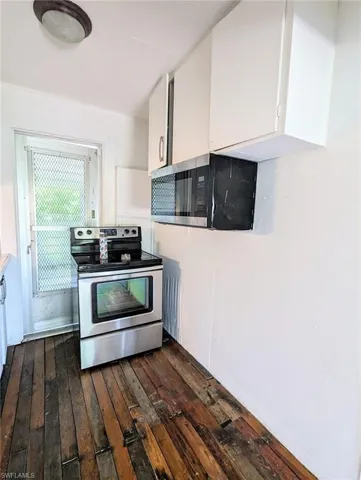 Kitchen with stainless steel appliances, white cabinets, and dark hardwood / wood-style floors