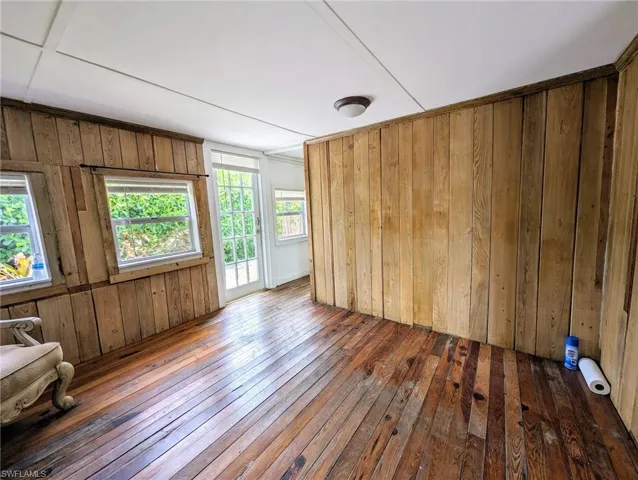 Empty room with wooden walls and dark hardwood / wood-style flooring