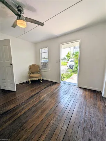 Unfurnished room with a healthy amount of sunlight, ceiling fan, and dark hardwood / wood-style floors