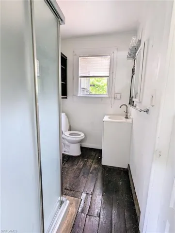 Bathroom featuring a shower with door, vanity, toilet, and hardwood / wood-style flooring