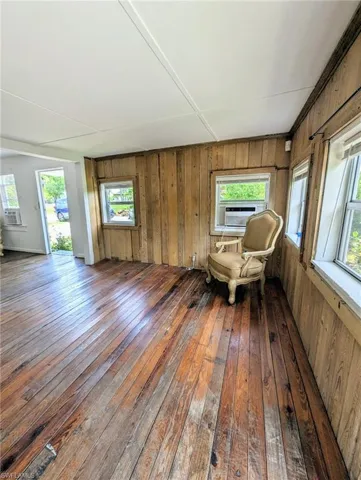 Unfurnished room featuring wooden walls and dark hardwood / wood-style floors