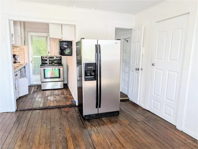 Kitchen with crown molding, stainless steel appliances, dark hardwood / wood-style flooring, backsplash, and white cabinetry