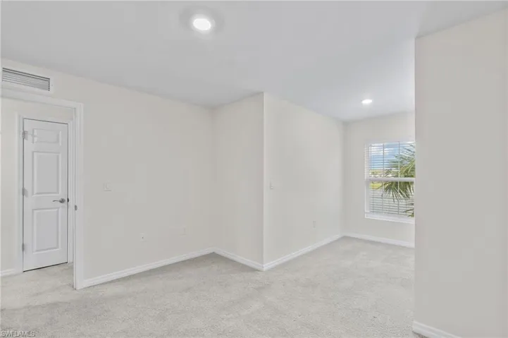 Empty room with light colored carpet and recessed lighting