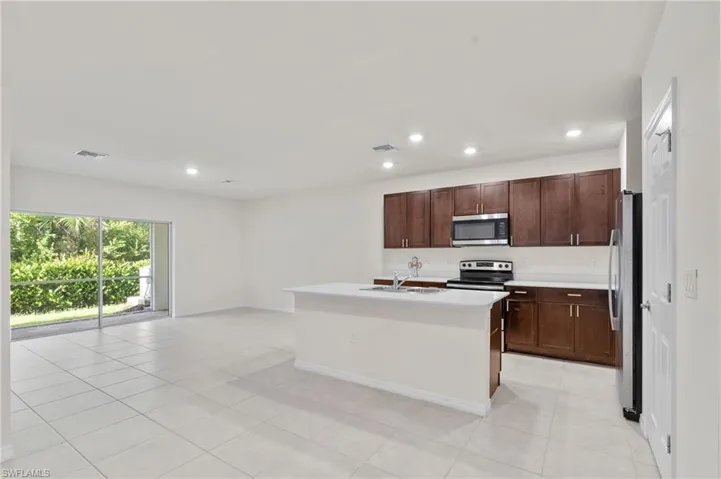 Kitchen with appliances with stainless steel finishes, recessed lighting, light tile patterned floors, an island with sink, and open floor plan