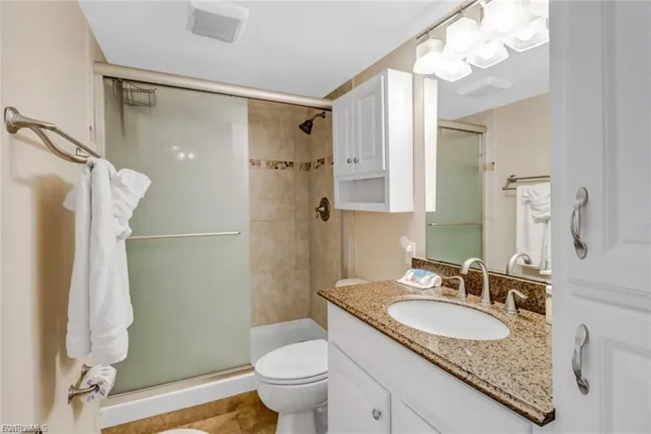 Full bath featuring a stall shower, vanity, and light tile patterned floors