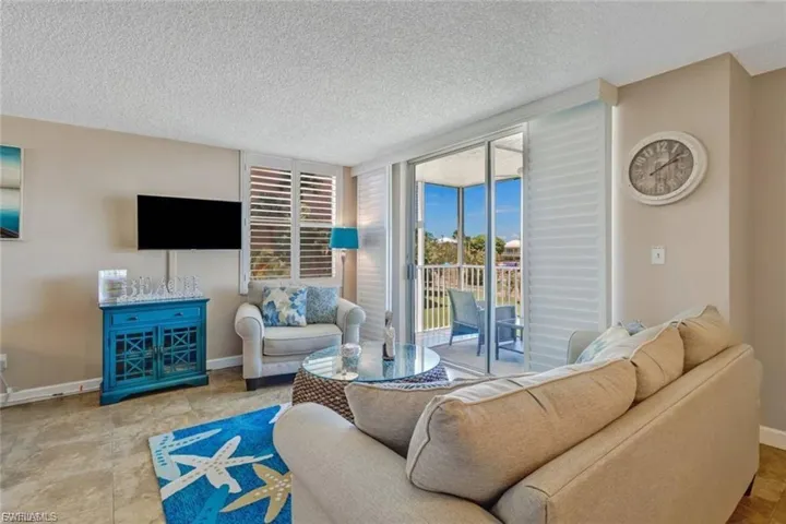 Living room with view of screened lanai, TV sitting area.