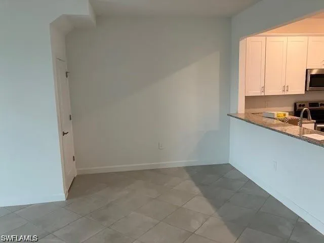Kitchen featuring light stone countertops, white cabinets, range, and tile patterned flooring