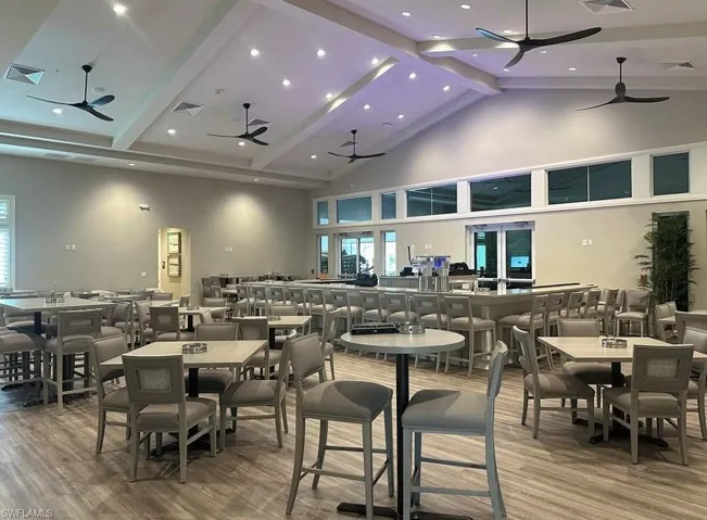Dining space with ceiling fan, high vaulted ceiling, wood-type flooring, and beamed ceiling