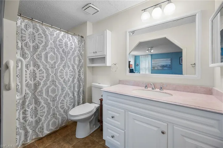 Bathroom with a textured ceiling, vanity, tile patterned floors, and curtained shower